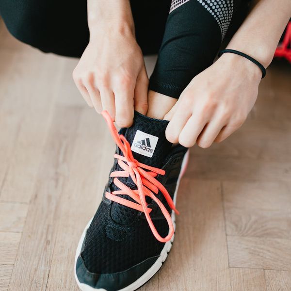 A yoga block and rolled mat on a wooden floor.